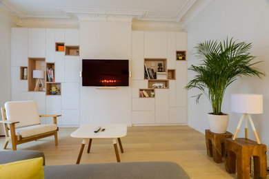 Idée de décoration pour un grand salon design ouvert avec une bibliothèque ou un coin lecture, un mur beige, parquet clair, aucune cheminée, un téléviseur fixé au mur et un sol beige.