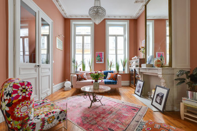 Diseño de salón para visitas ecléctico sin televisor con paredes rosas, suelo de madera en tonos medios, todas las chimeneas y suelo marrón