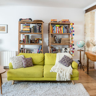 Cette photo montre un salon avec une bibliothèque ou un coin lecture chic de taille moyenne et fermé avec un mur blanc, un sol en bois clair, aucune cheminée et aucun téléviseur.