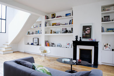 Cette photo montre un salon tendance avec un mur blanc, un sol en bois brun, une cheminée standard et un sol marron.