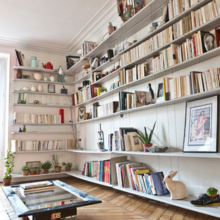 Réalisation d'un salon avec une bibliothèque ou un coin lecture design de taille moyenne et ouvert avec un mur blanc, un sol en bois brun, aucune cheminée et aucun téléviseur.