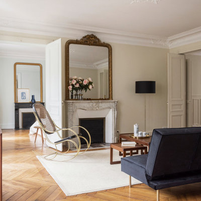 Example of a transitional medium tone wood floor and brown floor living room design in Paris with beige walls and a standard fireplace