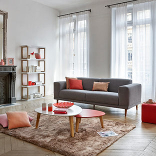 Cette image montre un grand salon design ouvert avec un mur blanc, un sol en bois clair, une cheminée standard, un manteau de cheminée en pierre et aucun téléviseur.