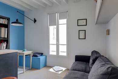 Cette image montre un petit salon ouvert avec un mur bleu, aucune cheminée, un téléviseur indépendant et un sol beige.
