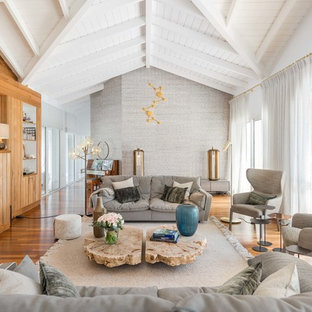 Aménagement d'un grand salon bord de mer avec un sol en bois brun, un sol marron, une salle de réception, un mur gris, une cheminée standard et un manteau de cheminée en bois.
