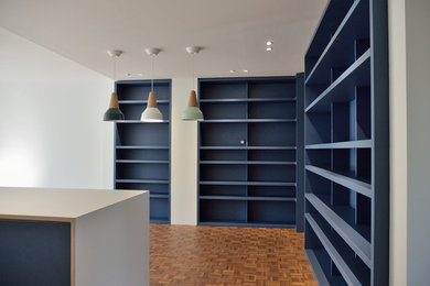 Источник вдохновения для домашнего уюта: гостиная комната в современном стиле с с книжными шкафами и полками, синими стенами и паркетным полом среднего тона
