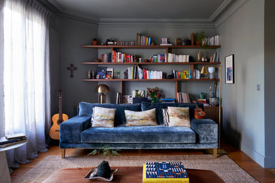 Exemple d'un salon tendance avec une bibliothèque ou un coin lecture, un mur gris, parquet foncé et aucun téléviseur.
