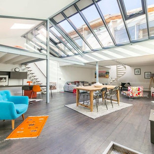 Cette image montre un grand salon bohème ouvert avec un mur blanc, un sol gris, un sol en bois foncé et aucun téléviseur.