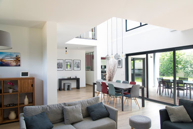 This is an example of a large contemporary open plan living room in Paris with white walls, light hardwood flooring and brown floors.