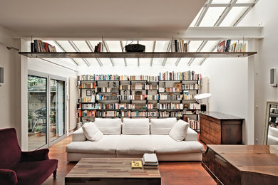 Réalisation d'un grand salon design ouvert avec une bibliothèque ou un coin lecture, un mur blanc, un sol en bois brun, aucune cheminée et un sol marron.