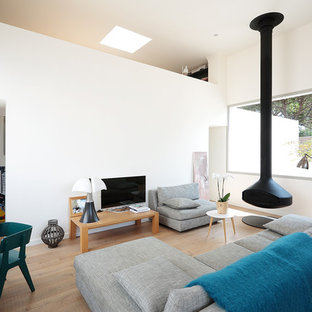 Cette photo montre un salon tendance ouvert et de taille moyenne avec un mur blanc, un sol en bois clair, un téléviseur indépendant et un poêle à bois.