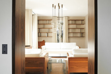 Exemple d'un grand salon tendance avec une bibliothèque ou un coin lecture, un mur beige, parquet clair et aucune cheminée.