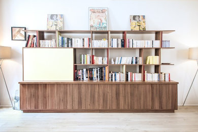 Cette photo montre un salon tendance avec une bibliothèque ou un coin lecture, un mur blanc, parquet clair, aucune cheminée et un téléviseur dissimulé.