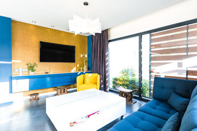 Cette photo montre un salon tendance ouvert avec un mur bleu, sol en béton ciré, un téléviseur fixé au mur et un sol gris.