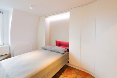 Idées déco pour un petit salon contemporain ouvert avec un mur blanc et tomettes au sol.