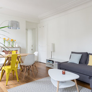 Cette image montre un salon avec une bibliothèque ou un coin lecture nordique fermé et de taille moyenne avec un mur blanc, un sol en bois brun, une cheminée standard, un manteau de cheminée en pierre, aucun téléviseur et un sol marron.