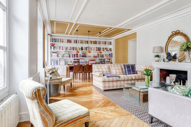 Aménagement d'un salon classique de taille moyenne et ouvert avec une bibliothèque ou un coin lecture, un mur jaune, parquet clair, une cheminée standard, un téléviseur indépendant, un sol marron et un plafond en lambris de bois.