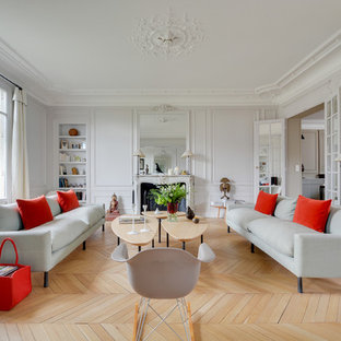 Cette photo montre un salon chic fermé avec une salle de réception, un mur gris, un sol en bois clair et une cheminée standard.
