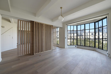 Modelo de salón abierto contemporáneo grande con suelo de madera clara y televisor retractable