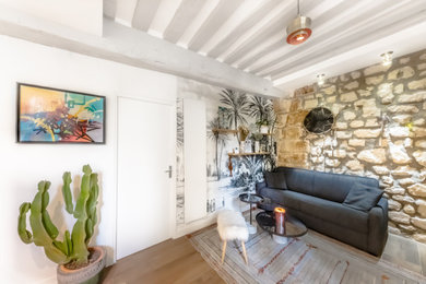 Cette photo montre un petit salon tendance ouvert avec un mur beige, un sol en bois brun, aucune cheminée, un téléviseur fixé au mur, un sol marron, poutres apparentes et du papier peint.
