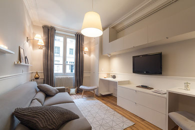 Modernes Wohnzimmer mit grauer Wandfarbe, braunem Holzboden und TV-Wand in Paris