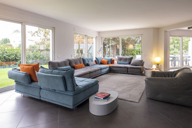 Modelo de salón abierto minimalista grande con paredes blancas, suelo de pizarra y suelo gris