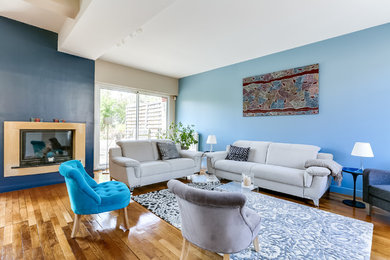 Cette photo montre un salon tendance avec un mur bleu, parquet clair, une cheminée standard et un manteau de cheminée en plâtre.