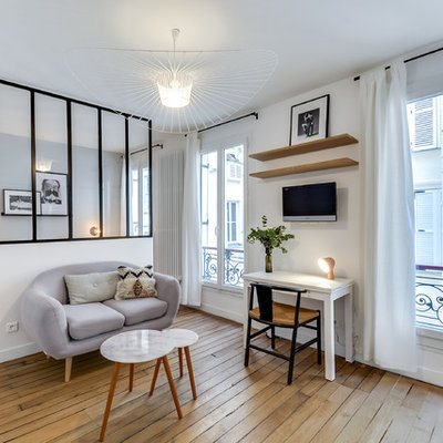 Example of a mid-sized danish light wood floor living room design in Paris with white walls and no fireplace