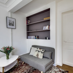 Inspiration pour un petit salon avec une bibliothèque ou un coin lecture design ouvert avec un mur blanc, un sol en bois brun, aucune cheminée et aucun téléviseur.