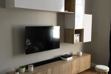 Aménagement d'un salon moderne de taille moyenne et ouvert avec un mur beige, parquet clair et un téléviseur fixé au mur.