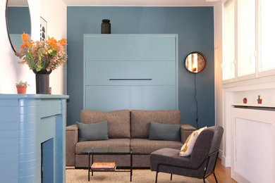 Exemple d'un petit salon moderne ouvert avec un mur bleu, parquet clair, une cheminée standard, un manteau de cheminée en brique et un sol gris.