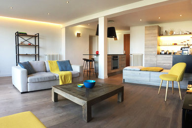 Cette photo montre un grand salon tendance ouvert avec un mur blanc, un sol en bois brun, aucune cheminée, un téléviseur dissimulé et un sol marron.
