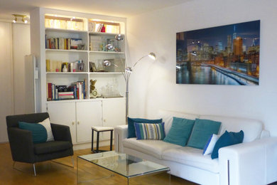 Idée de décoration pour un salon design de taille moyenne avec une bibliothèque ou un coin lecture, un mur blanc et parquet clair.
