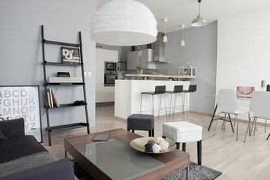 Cette photo montre un grand salon tendance ouvert avec un mur gris, parquet clair et canapé noir.