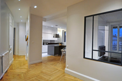 Imagen de salón abierto contemporáneo de tamaño medio con suelo de madera clara, televisor colgado en la pared, suelo beige, paredes grises, bandeja y boiserie