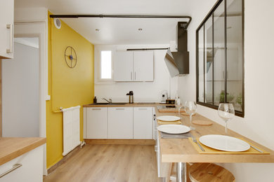 Idée de décoration pour un salon urbain de taille moyenne et ouvert avec un mur jaune, sol en stratifié, aucune cheminée, un téléviseur fixé au mur et un sol marron.