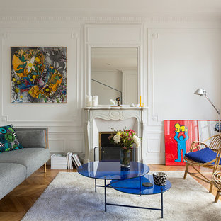 Inspiration pour un salon design avec une salle de réception, un mur blanc, un sol en bois brun, une cheminée standard, aucun téléviseur et un manteau de cheminée en pierre.