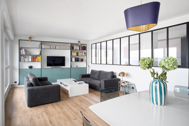 Modelo de salón abierto actual con paredes blancas, suelo de madera clara, televisor independiente y suelo beige