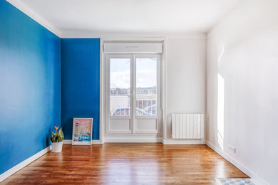 Cette image montre un salon minimaliste de taille moyenne et fermé avec un mur bleu, sol en stratifié et un sol marron.