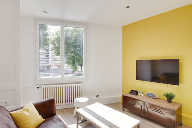 Réalisation d'un salon urbain de taille moyenne et ouvert avec un mur jaune, sol en stratifié, aucune cheminée, un téléviseur fixé au mur et un sol marron.