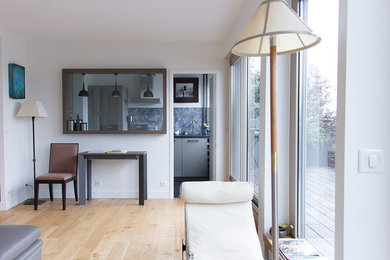 Aménagement d'un petit salon moderne fermé avec un mur blanc, parquet clair et un sol beige.
