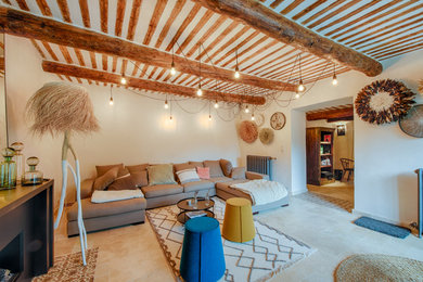 Cette image montre un salon méditerranéen avec un mur blanc, un sol beige et poutres apparentes.