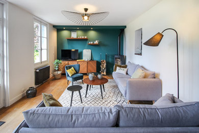 Cette photo montre un salon moderne ouvert avec un mur vert, parquet foncé et un téléviseur dissimulé.