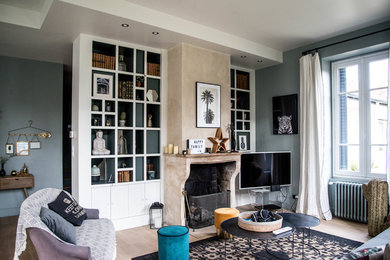 Idée de décoration pour un salon design ouvert avec un mur gris, parquet clair, une cheminée standard, un manteau de cheminée en pierre, un téléviseur indépendant et un sol beige.