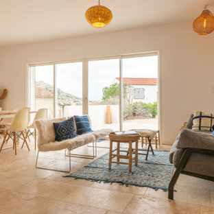 Idées déco pour un salon bord de mer avec un mur blanc, un sol en travertin, aucune cheminée, aucun téléviseur et un sol beige.