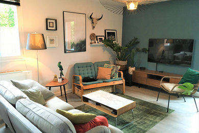 Imagen de salón abierto bohemio pequeño con paredes azules, suelo vinílico, televisor colgado en la pared y suelo gris