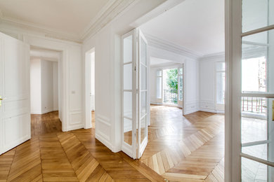 Cette photo montre un grand salon chic ouvert avec une salle de réception, un mur blanc, parquet clair, une cheminée standard et un sol marron.