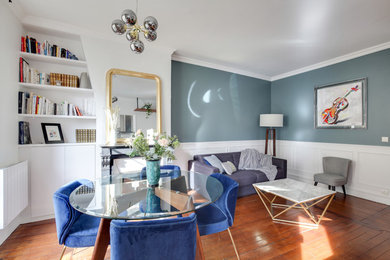 Mittelgroßes, Offenes Klassisches Wohnzimmer mit blauer Wandfarbe, dunklem Holzboden, Kamin, Kaminumrandung aus Stein, freistehendem TV und braunem Boden in Paris