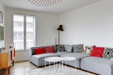 Imagen de salón abierto nórdico de tamaño medio con paredes blancas, suelo laminado y televisor colgado en la pared
