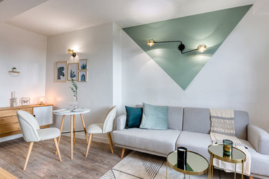 Imagen de salón cerrado escandinavo pequeño sin chimenea con paredes verdes, suelo de madera clara, televisor colgado en la pared y suelo gris